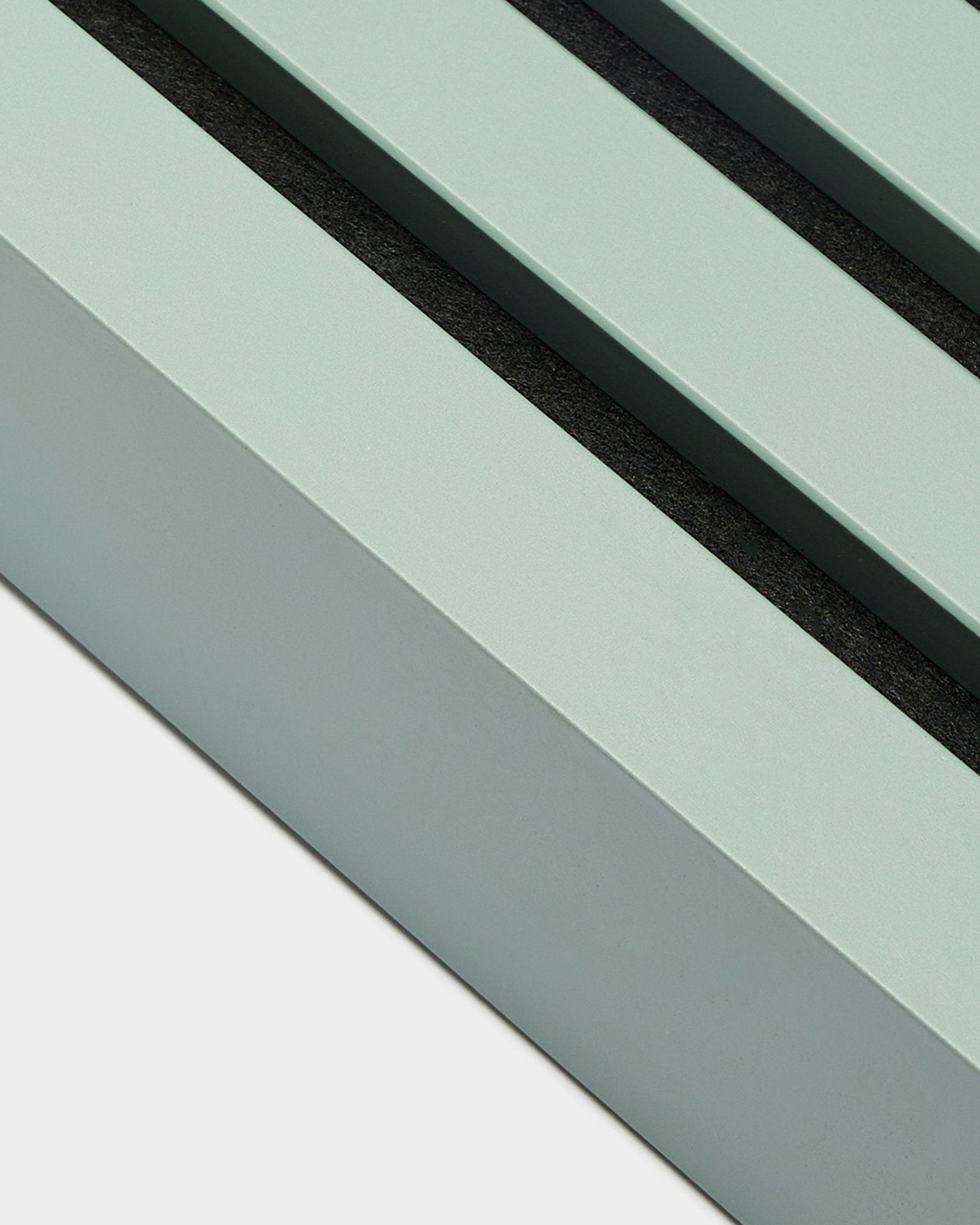 Close-up van WoodUpp Akupanel installatieaccessoire: eindlamel in Cloud, 6,7 cm breed, mintgroen MDF-frame met twee black groeven op een witte achtergrond.