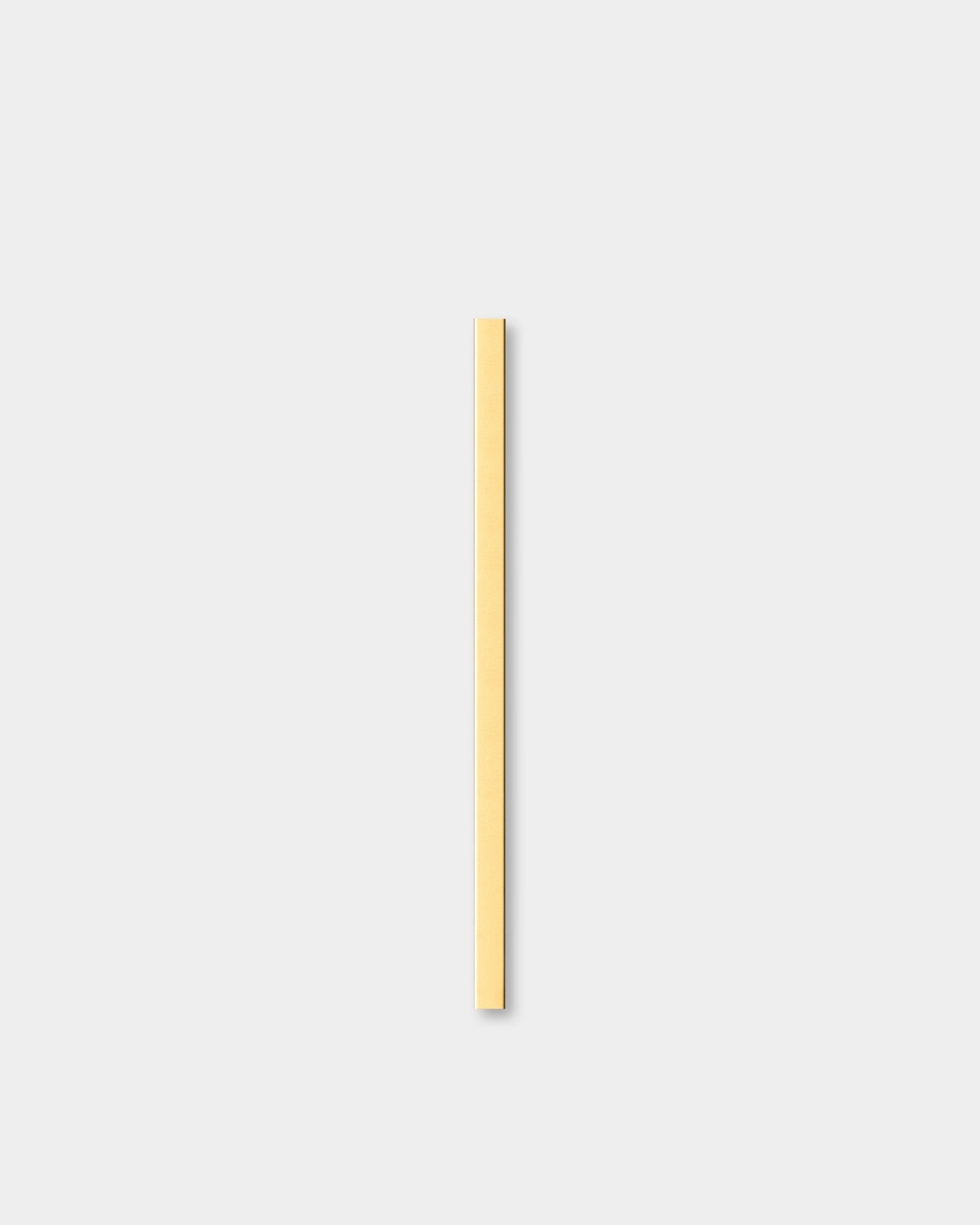 De Liva | Cover in brass, 60 cm van WoodUpp, een Akoestisch paneel, staat verticaal tegen een lichtgrijze achtergrond naast decoratieve wandlijsten.
