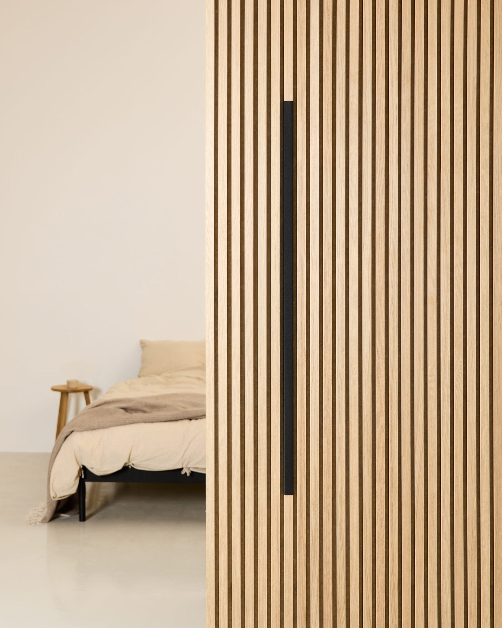 Minimalistische slaapkamer met een beige bed, een houten nachtkastje en een WoodUpp Akupanel Black Aluminium 120 cm akoestisch paneel aan de muur.