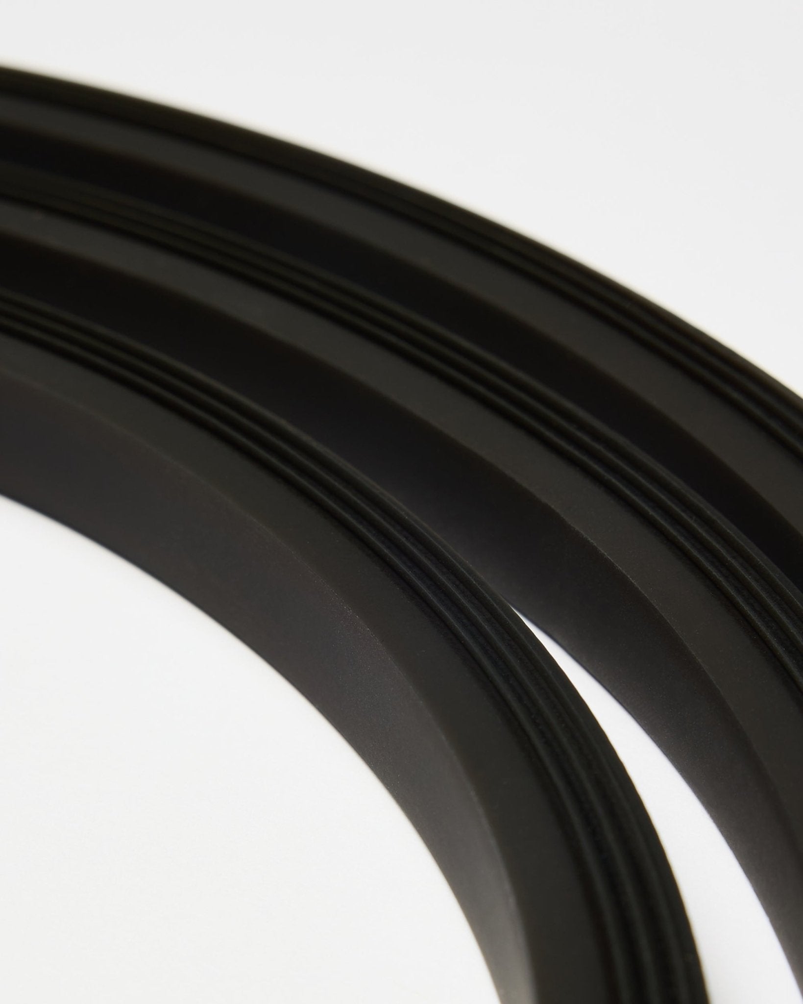 Close-up van de black Lumi LED-strip van WoodUpp (300 cm), geplaatst in gebogen lijnen op een witte achtergrond, als aanvulling op de minimalistische Akupanel Akoestisch paneel stijl.