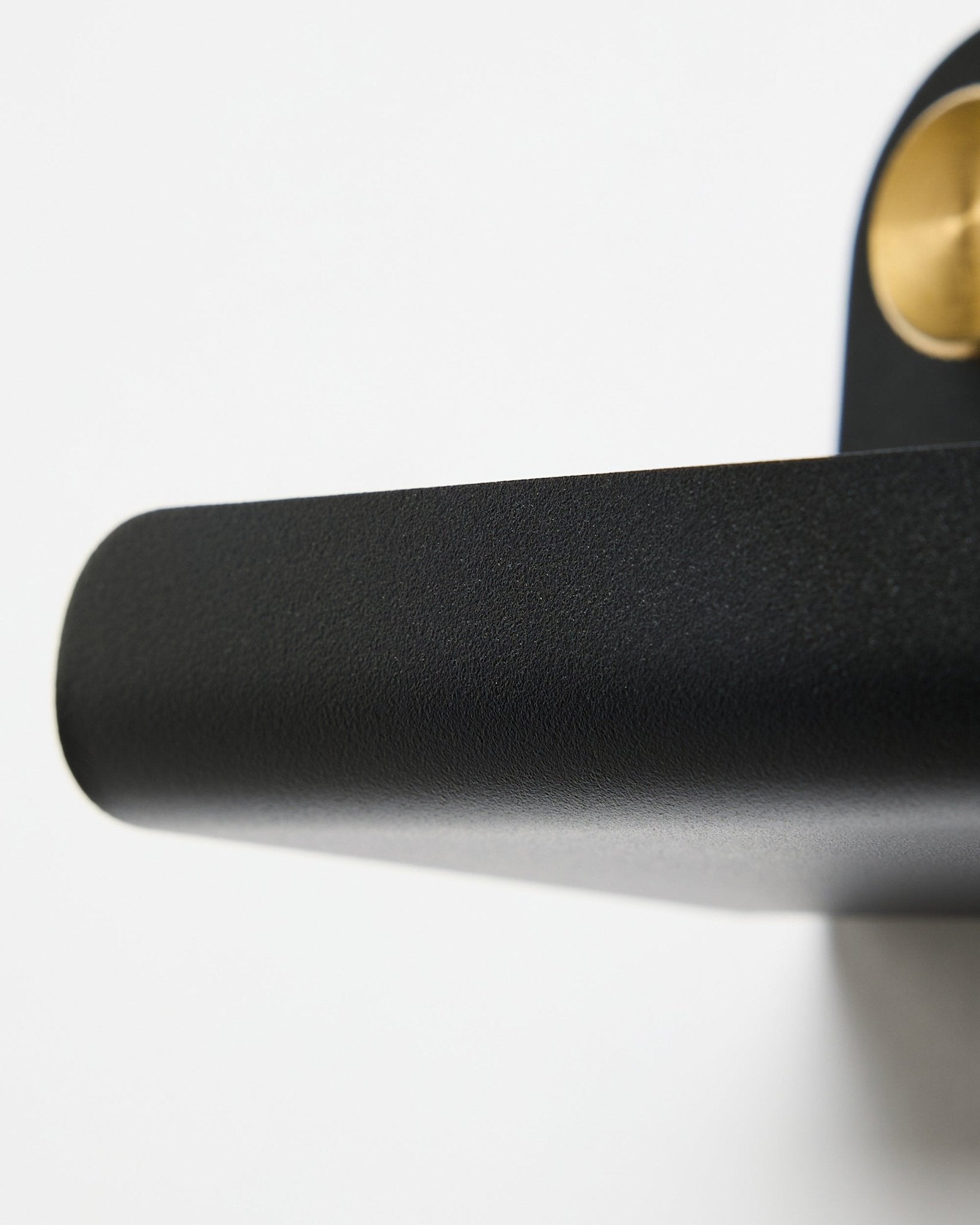 Close-up van een black deurklink en de WoodUpp Norr | Narrow Shelf in black, 51,9 cm, geplaatst tegen een witte achtergrond.