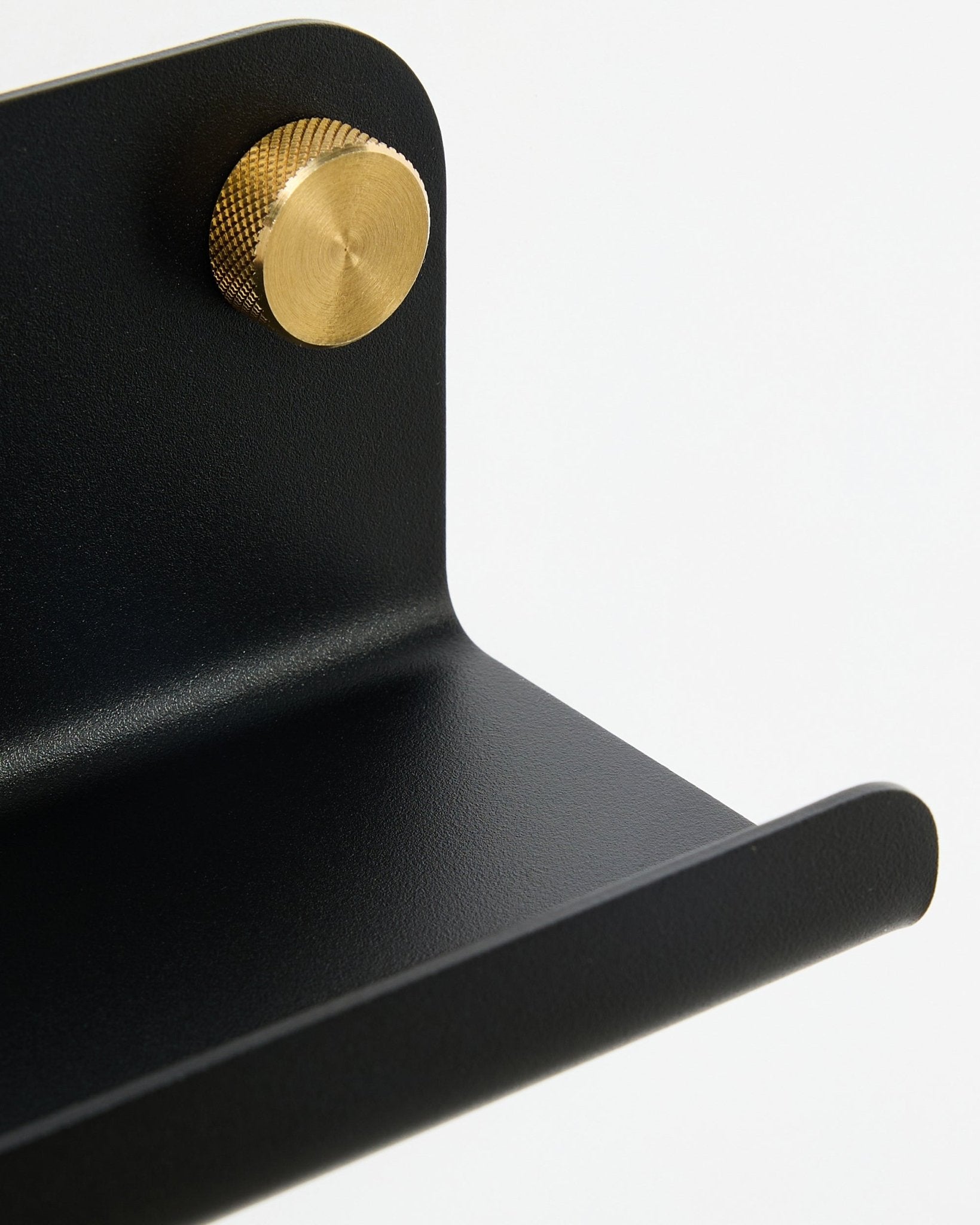 Close-up van de WoodUpp Norr Narrow shelf, 35,9 cm, black steel met afgeronde rand en gouden knop, weergegeven tegen een witte achtergrond.