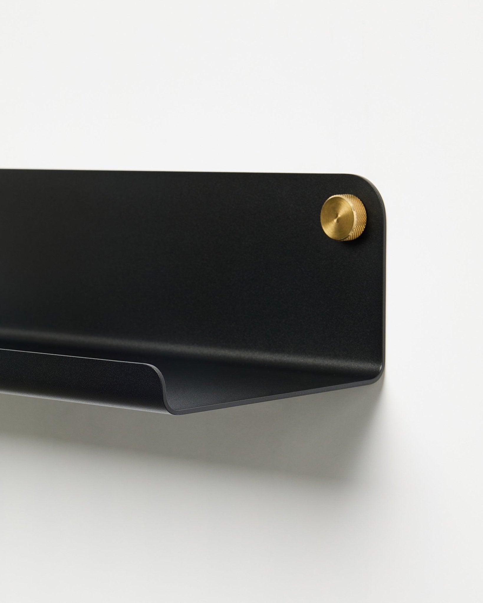 Close-up van de WoodUpp Norr Wide Shelf-accessoire (51,9 cm) in gepoedercoat black metaal met gouden schroef, geplaatst tegen een effen witte achtergrond.