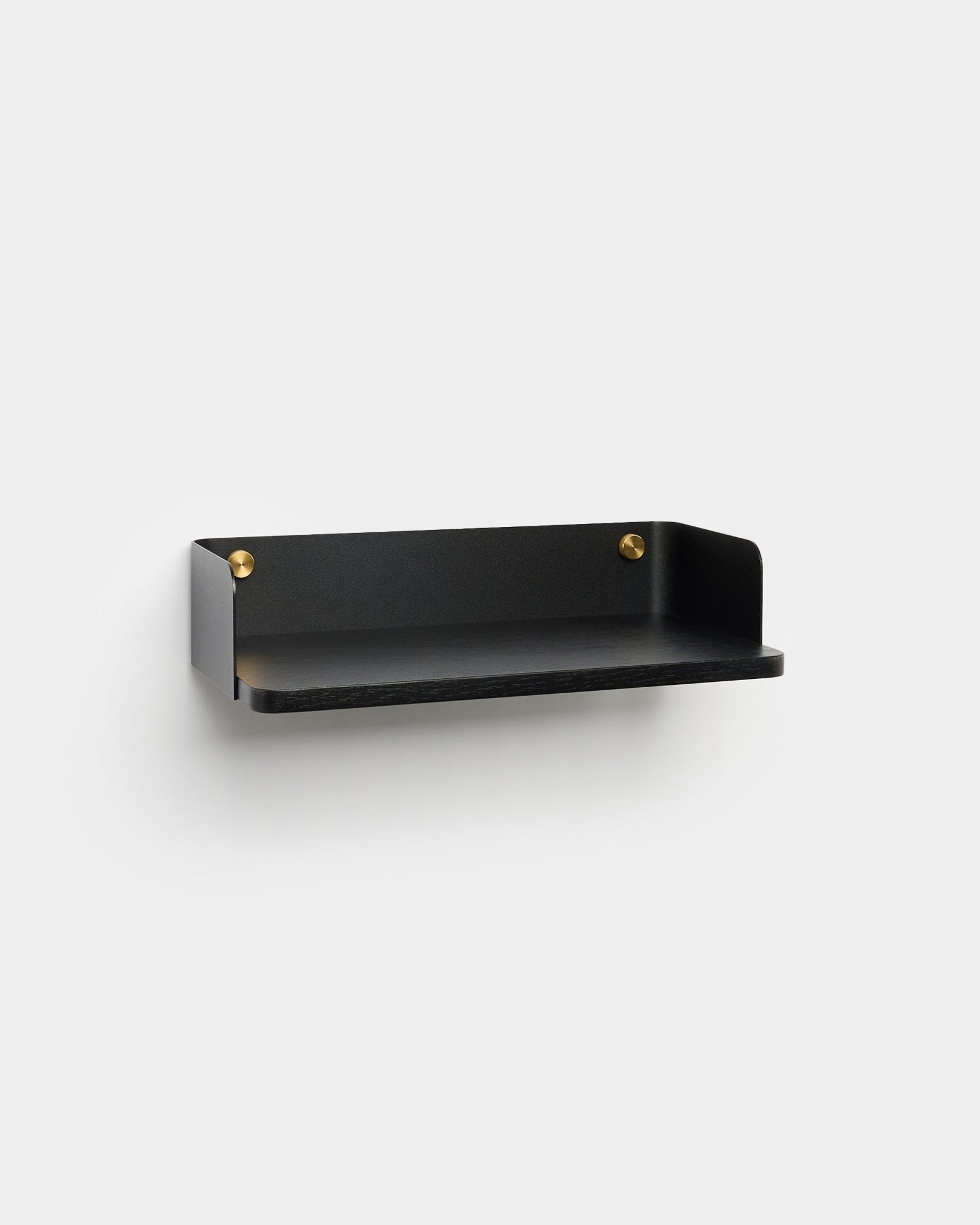 De Linn Bookshelf van WoodUpp, in een minimalistische afwerking in black met brass montageschroeven, is bevestigd aan een lichtgrijze muur en past mooi bij een Scandinavisch interieur.
