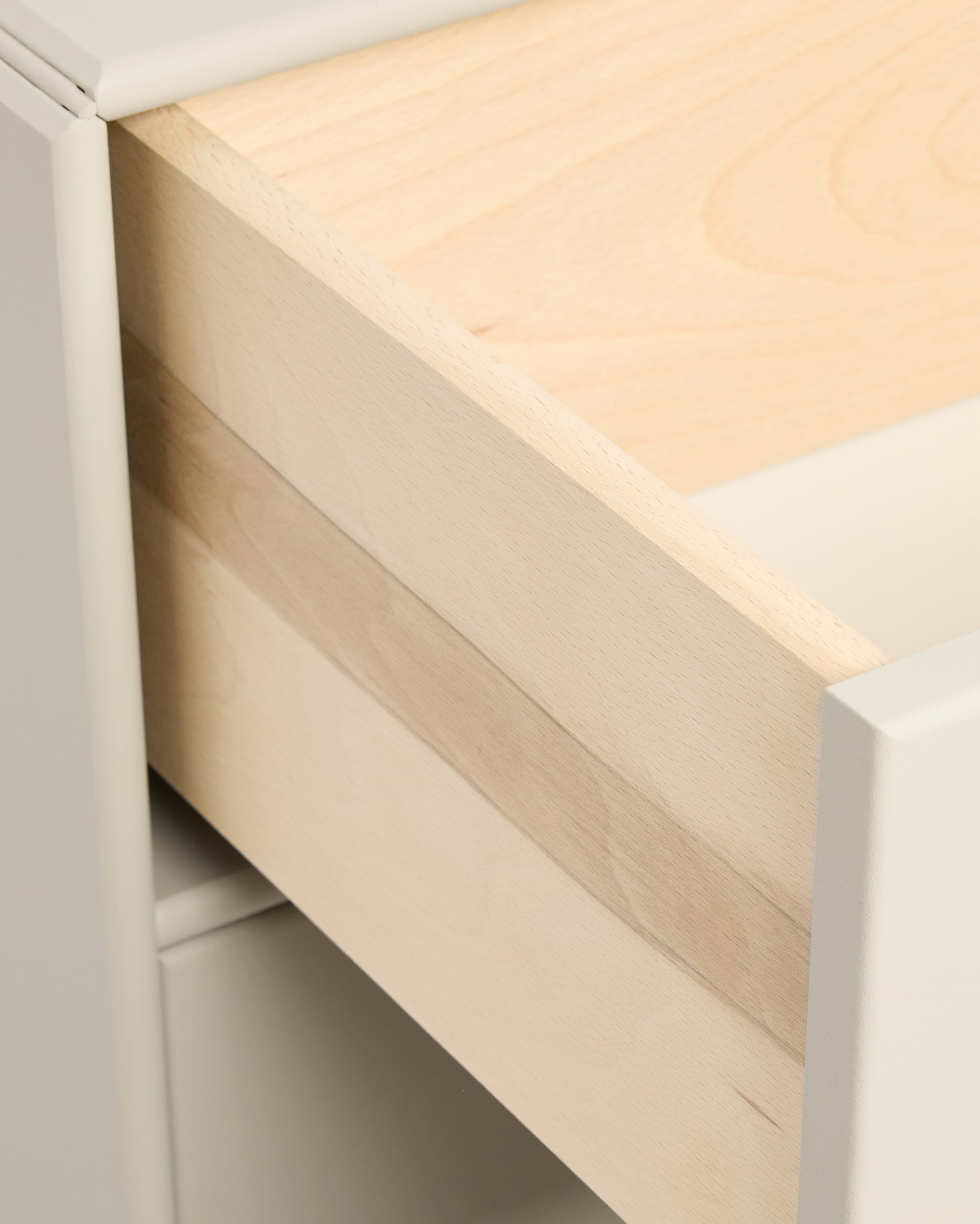 Close-up van een gedeeltelijk geopende beige Arka-boekenkastlade van WoodUpp in een witte kast, afgebeeld met handgrepen uit de CREATE-collectie.