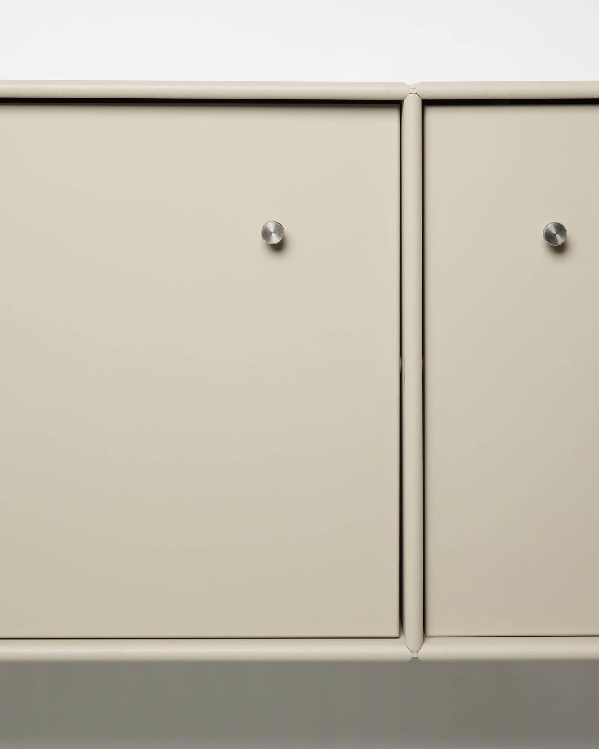 Arka tv-meubel van WoodUpp met beige metalen kastdeuren, ronde zilveren knoppen, modulair ontwerp en geïntegreerde kabelgeleiding, geschikt voor Scandinavische interieurs.
