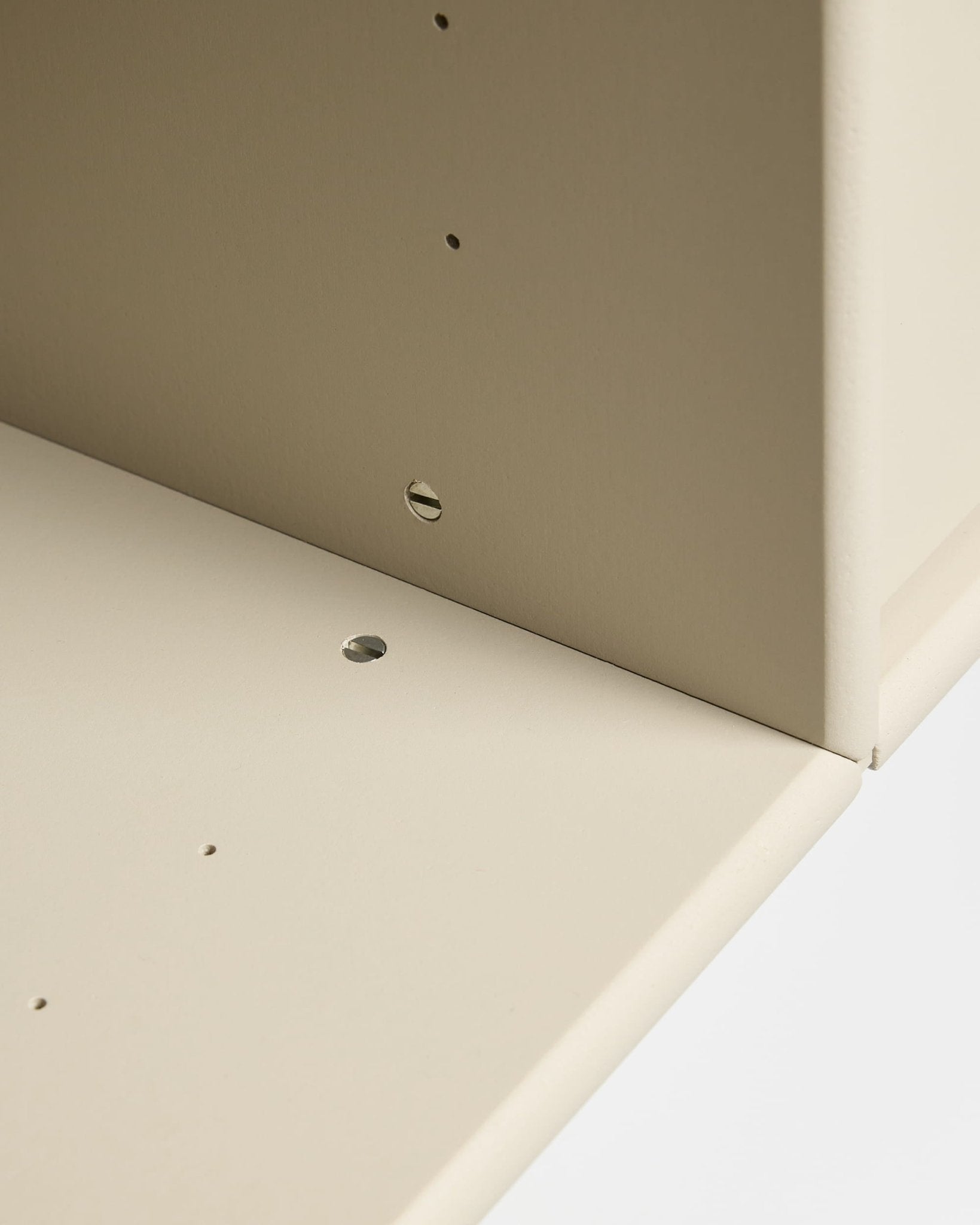 Close-up van twee beige Arka TV-consoleborden van WoodUpp, haaks aan elkaar bevestigd met voorgeboorde gaten voor modulaire montage en kabelbeheer.