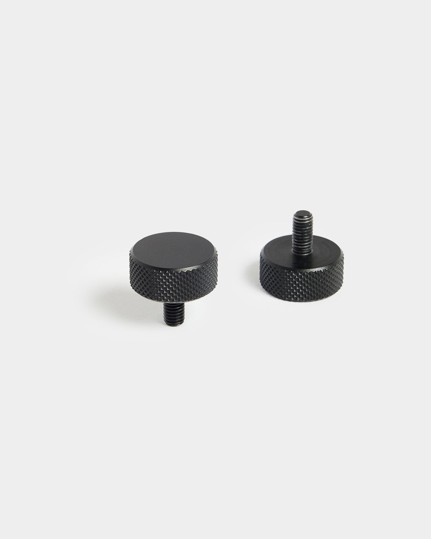 Een paar black WoodUpp Finger-schroeven (M5x10 mm, 20x8.8) met gekartelde randen, ontworpen voor gebruik met Akoestisch paneel accessoires, op een effen witte achtergrond.