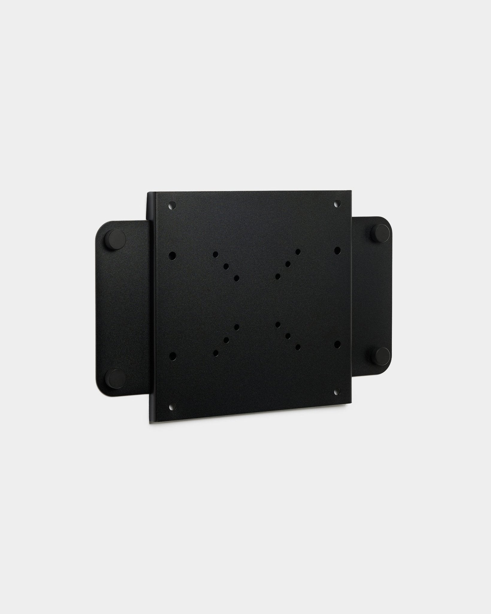 De Fjell | TV Mount (small) van WoodUpp, een black metalen beugel met meerdere schroefgaten en een magnetische vergrendeling, weergegeven op een witte achtergrond.