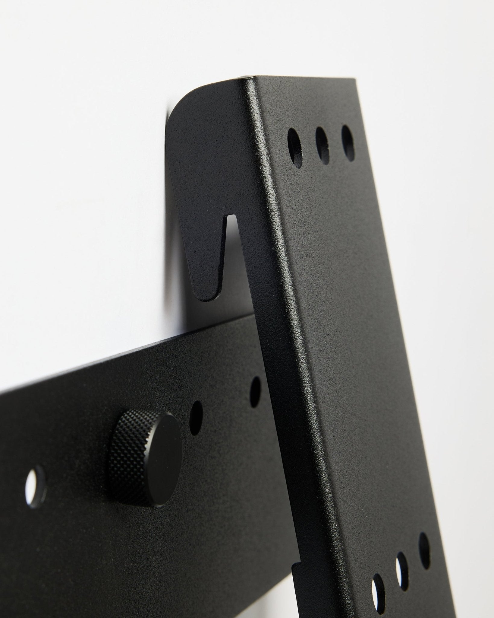 WoodUpp Fjell tv-mount (large), een black metalen beugel voor 85-inch tv's met VESA 600x400, gemonteerd op een witte muur.