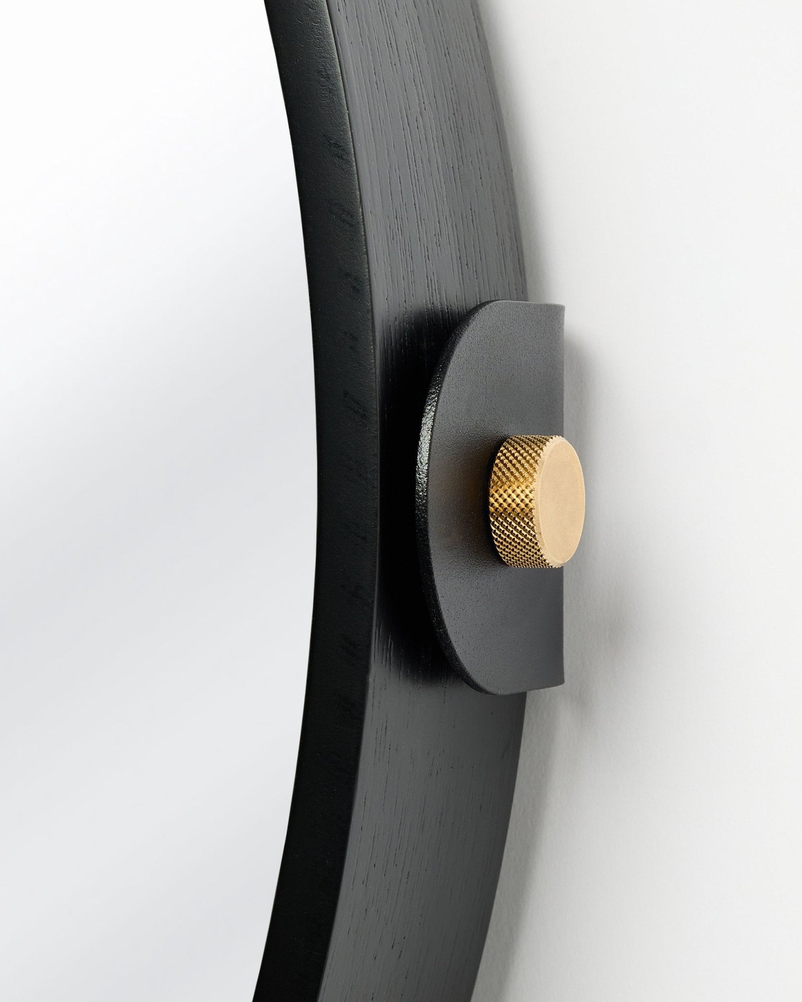 Detail van de Linn | Mirror / Black Oak Akoestisch paneel van WoodUpp, aan de muur gemonteerd met een gouden knop en verstelbare kanteling.
