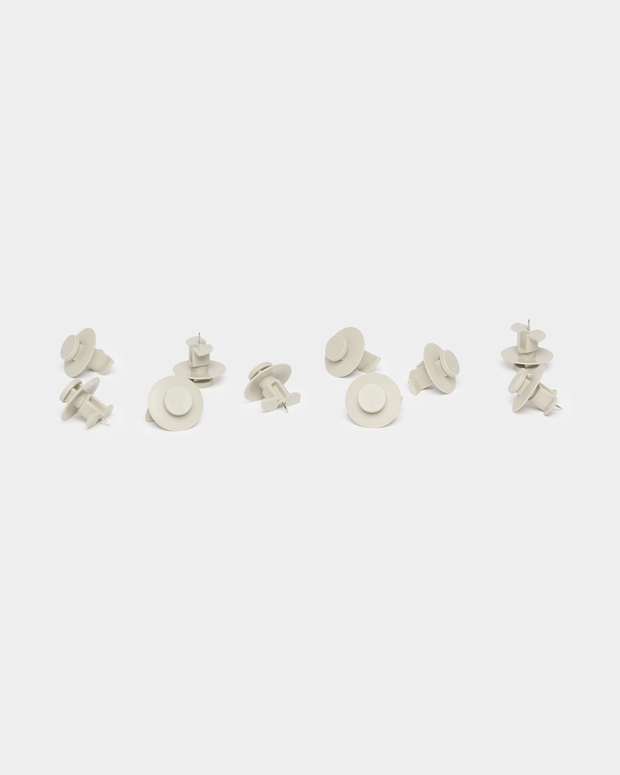Tien beige Dupps-pinnen van WoodUpp, die worden gebruikt als accessoires voor Akupanel, zijn losjes gegroepeerd op een effen witte achtergrond.