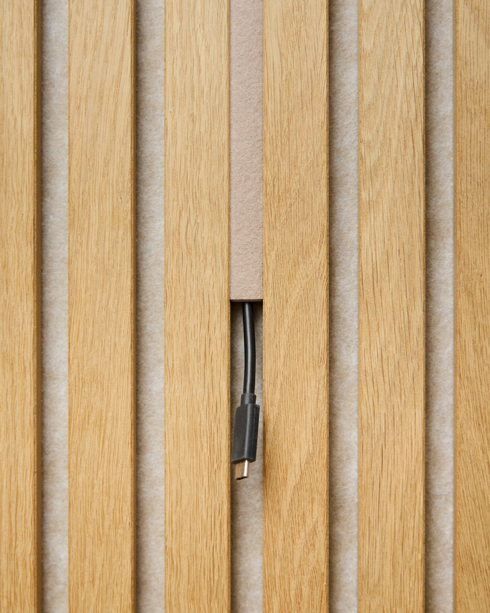 Dupps Pop-on Cable Cover (beige, set van 3) van WoodUpp werkt kabels weg tussen Akoestisch paneel latten, waarbij alleen de connector zichtbaar blijft voor een strakke afwerking.