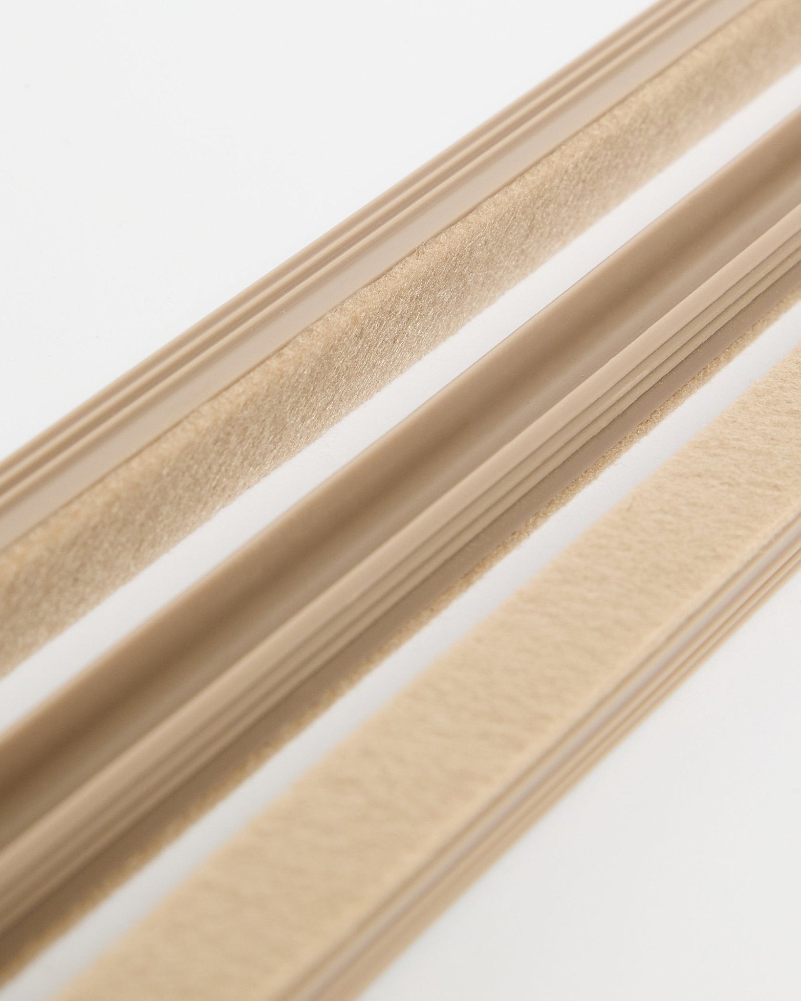 Beige WoodUpp Dupps Pop-on Cable Covers (3-pack) met vilttextuur en zelfklevende achterkant, weergegeven op een wit oppervlak voor het organiseren van snoeren.