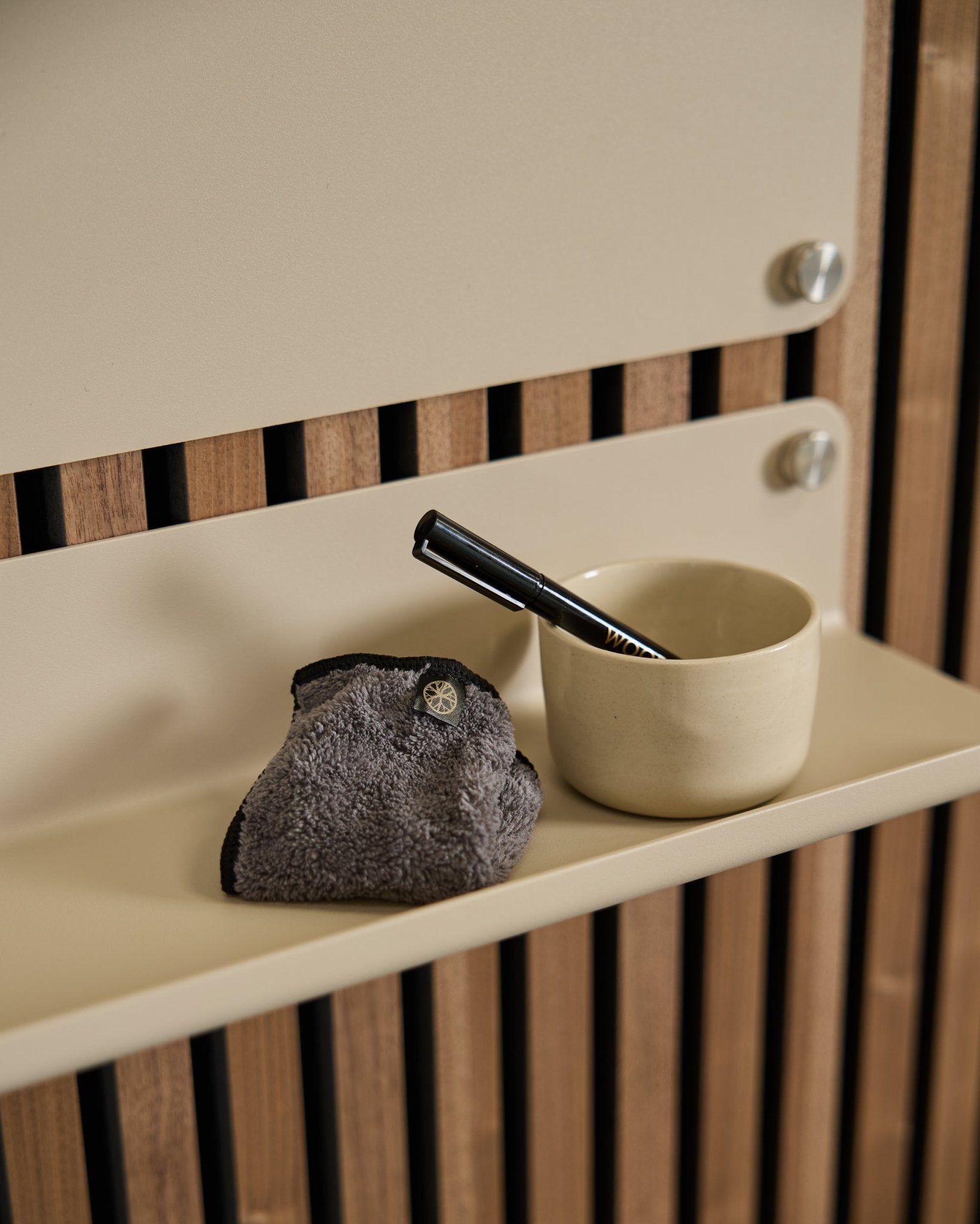 De WoodUpp Norr Blackboard-set bevat een small beige beker, een borstel met black handvat en een schoonmaakdoek op een beige plank met Scandinavische akoestische houten panelen.
