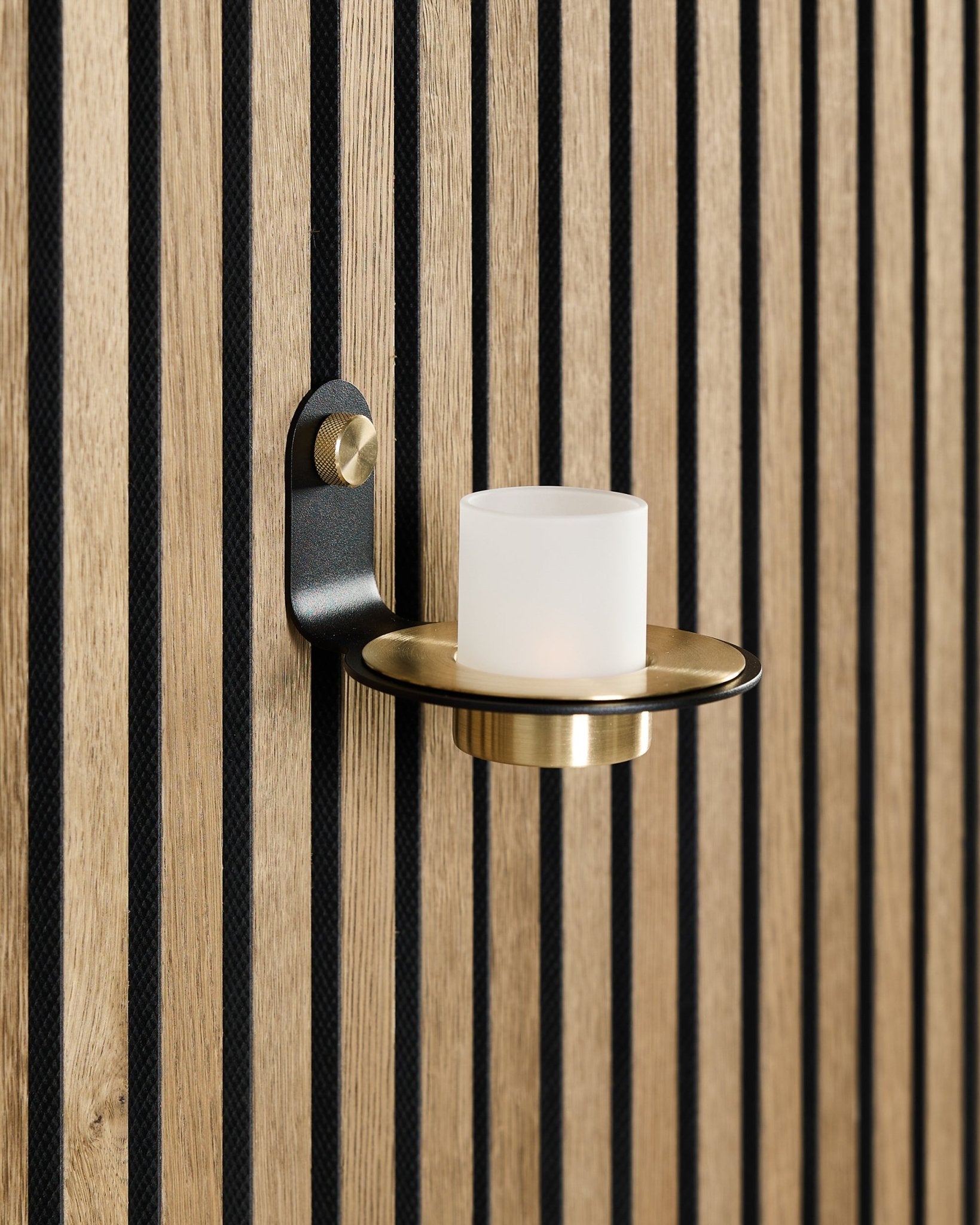 De Norr kaarsenhouder in black en brass van WoodUpp is gemonteerd op een Scandinavisch Akupanel akoestisch houten paneel met vertical black latten.