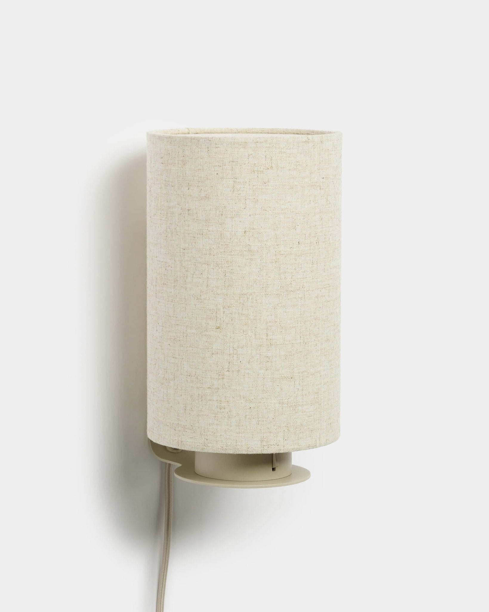 Feya | Wall Lamp van WoodUpp met een cilindervormige kap van linnen-katoen en een zichtbaar wit snoer, in beige afwerking, ontworpen als aanvulling op akoestische houten panelen.