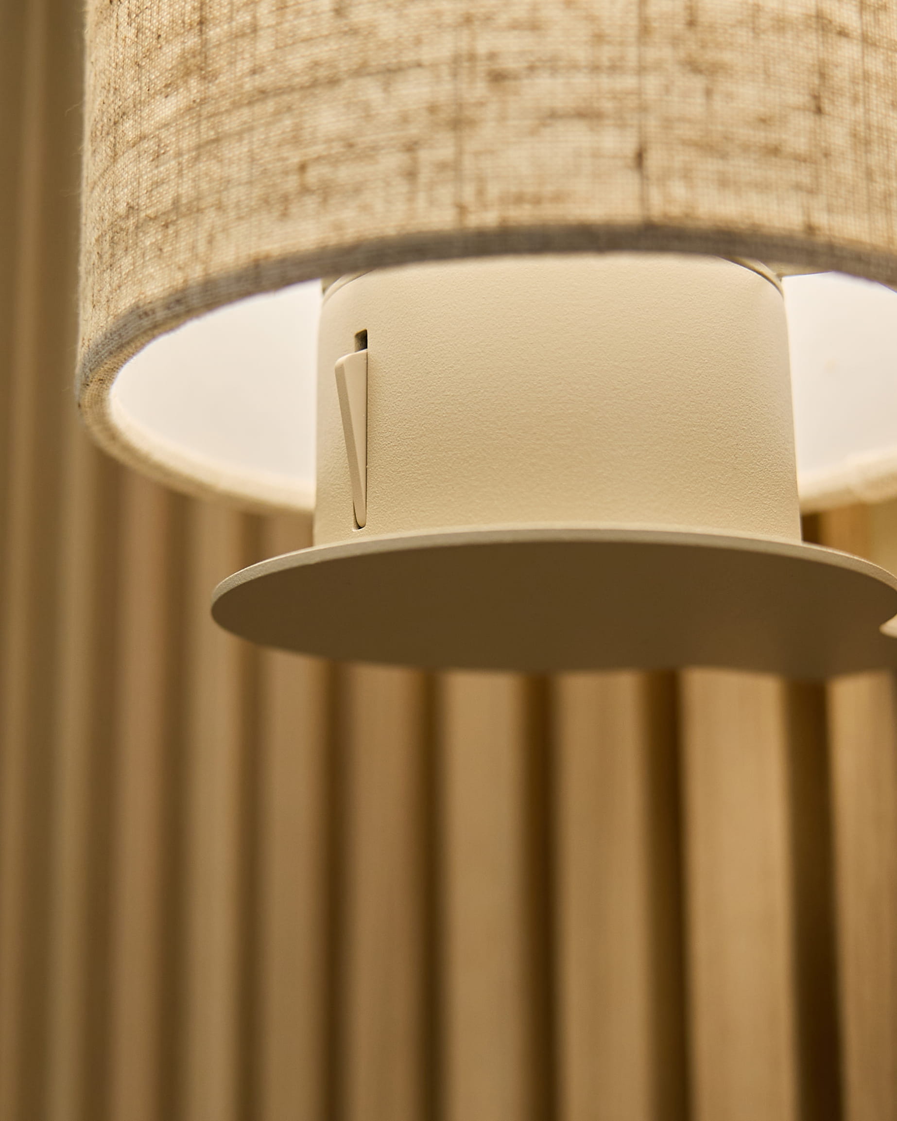 Close-up van de Feya wandlamp in Beige/Beige van WoodUpp, met een kap van linnen-katoen en een cilindervormige armatuur, gemonteerd op vertical beige akoestische panelen.
