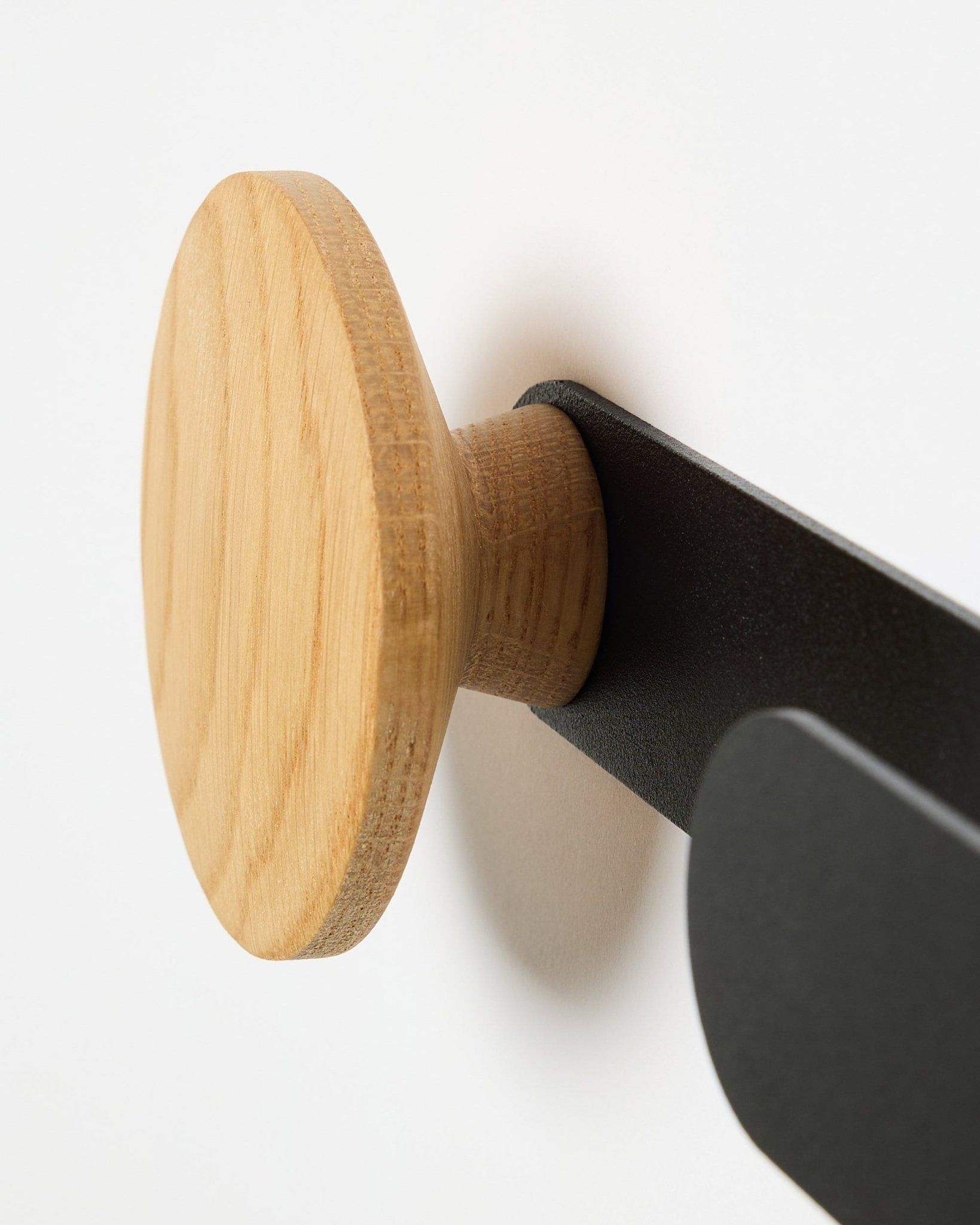 Close-up van de WoodUpp Linn Horizontal Hanger in natural oak op een black metalen beugel, ontworpen voor Akupanel akoestische panelen of als functionele wandhaak.