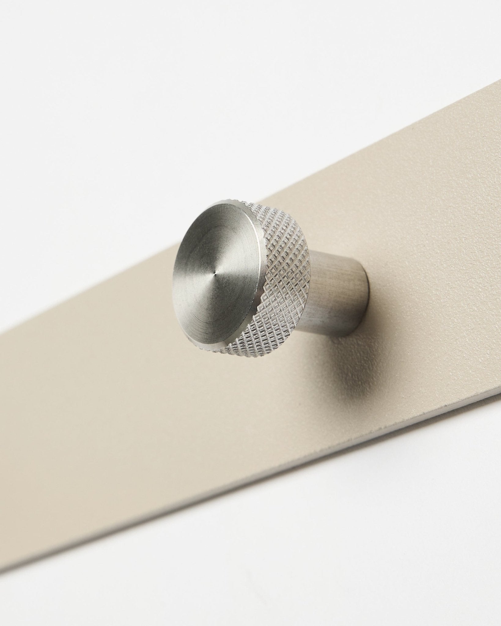 Norr kapstok in beige en roestvrij staal steel van WoodUpp, accessoire voor de Akupanel collectie, getoond in close-up tegen een witte achtergrond.