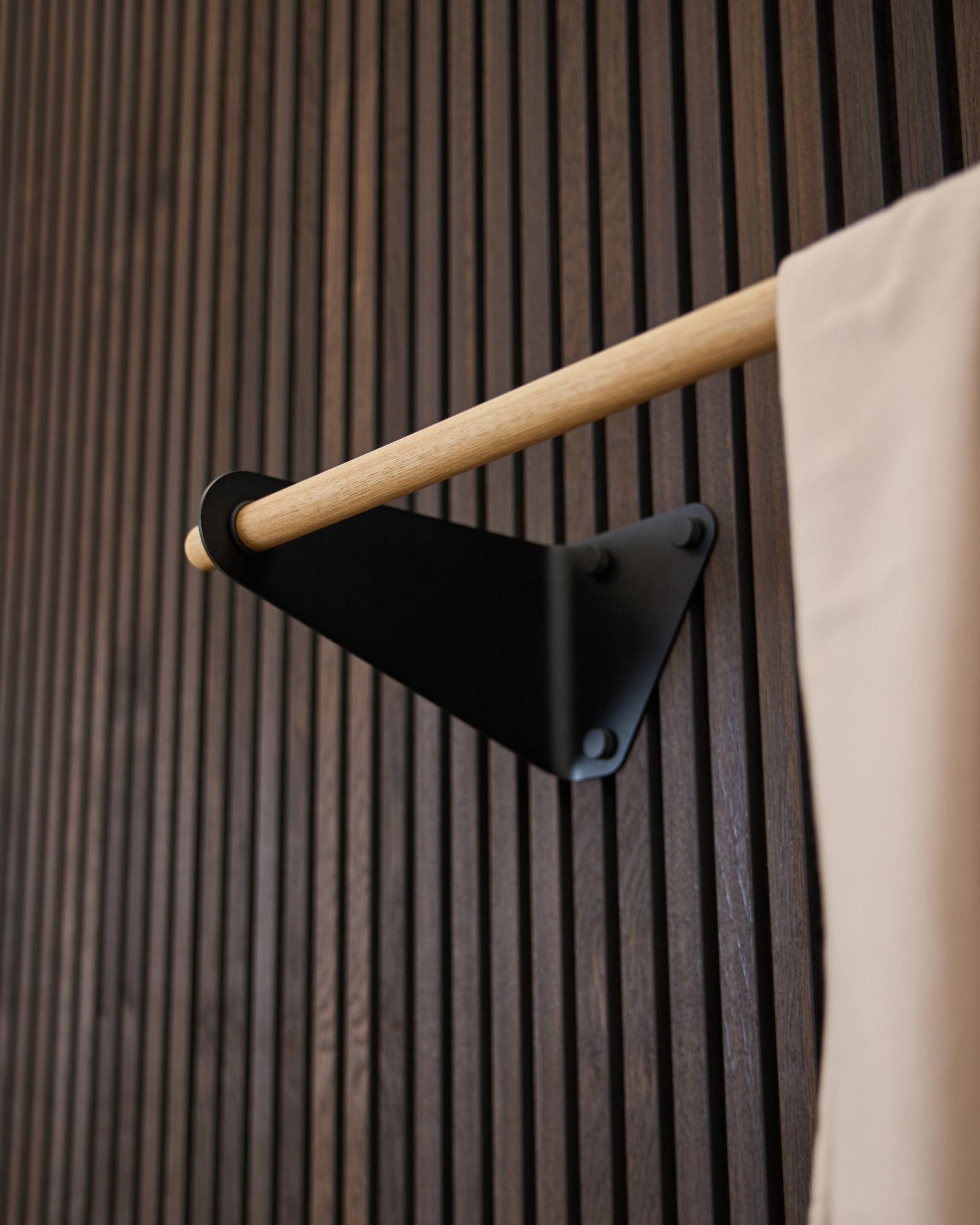 Linn kapstok van WoodUpp in black (115,9 cm), gemonteerd op een donkere gegroefde Akupanel Akoestisch paneel, met beige stoffen accent en black beugel.