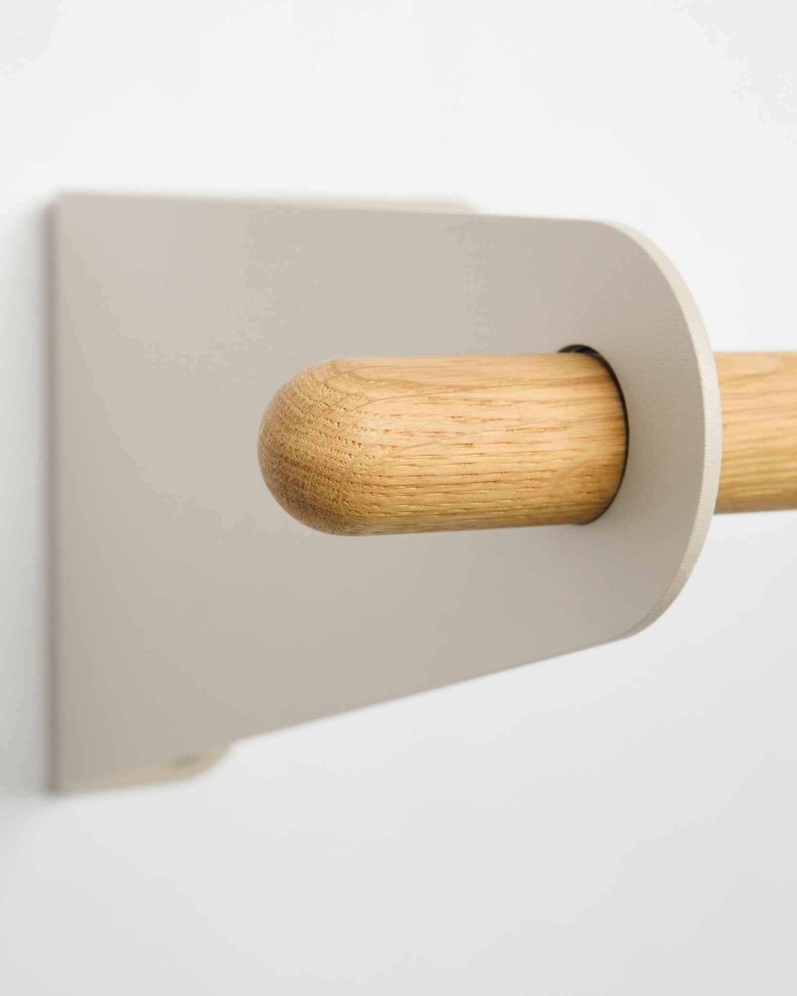 Close-up van de WoodUpp Linn kapstok in beige, 115,9 cm, met een licht beige metalen beugel gemonteerd op een witte muur. Scandinavisch minimalistisch designaccessoire.