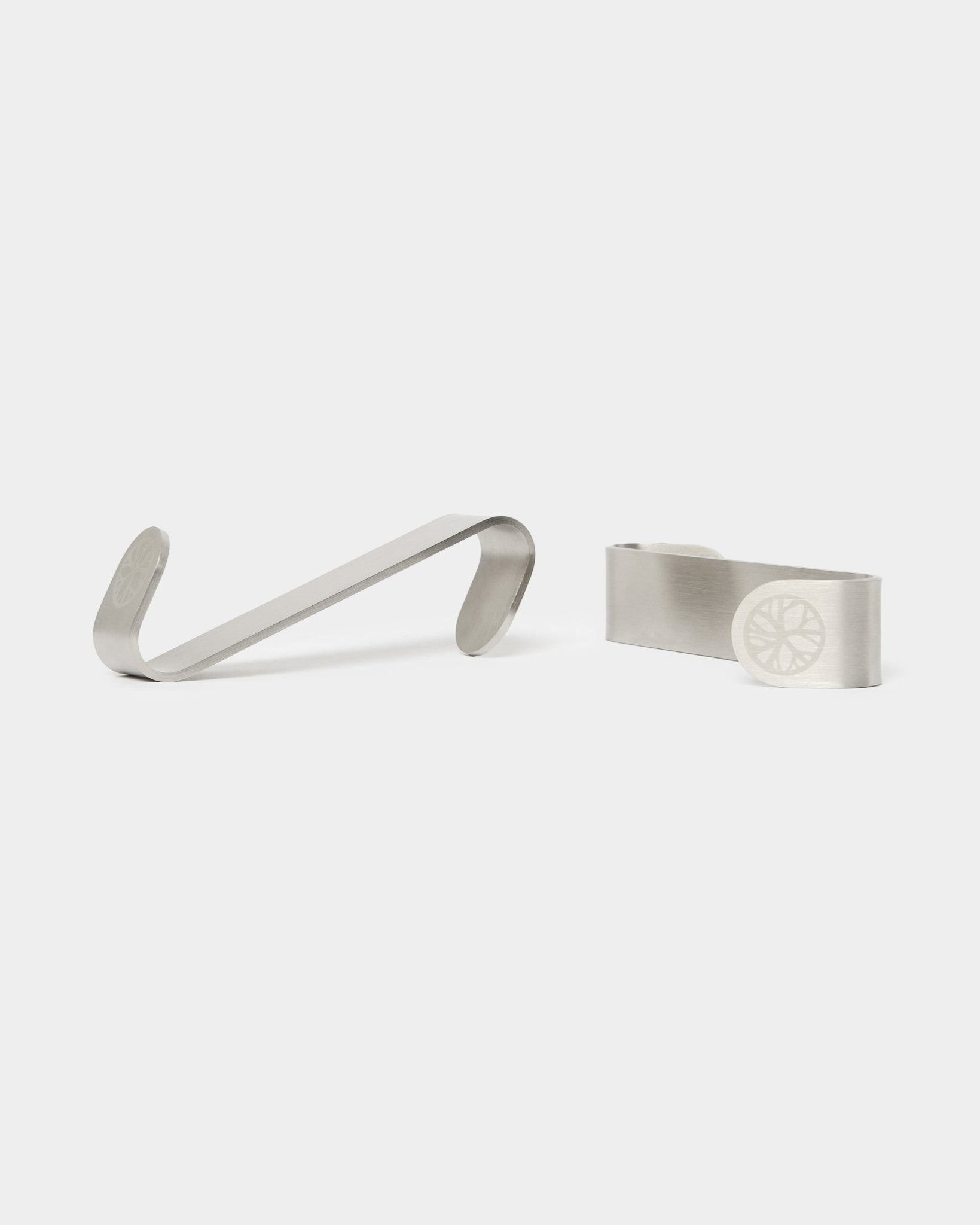 WoodUpp Alva S-Hook BM1 en BM2 geldclips, twee roestvrijstalen steel accessoires met gegraveerde wielmotieven, ontworpen voor Scandinavische akoestische houten panelen.