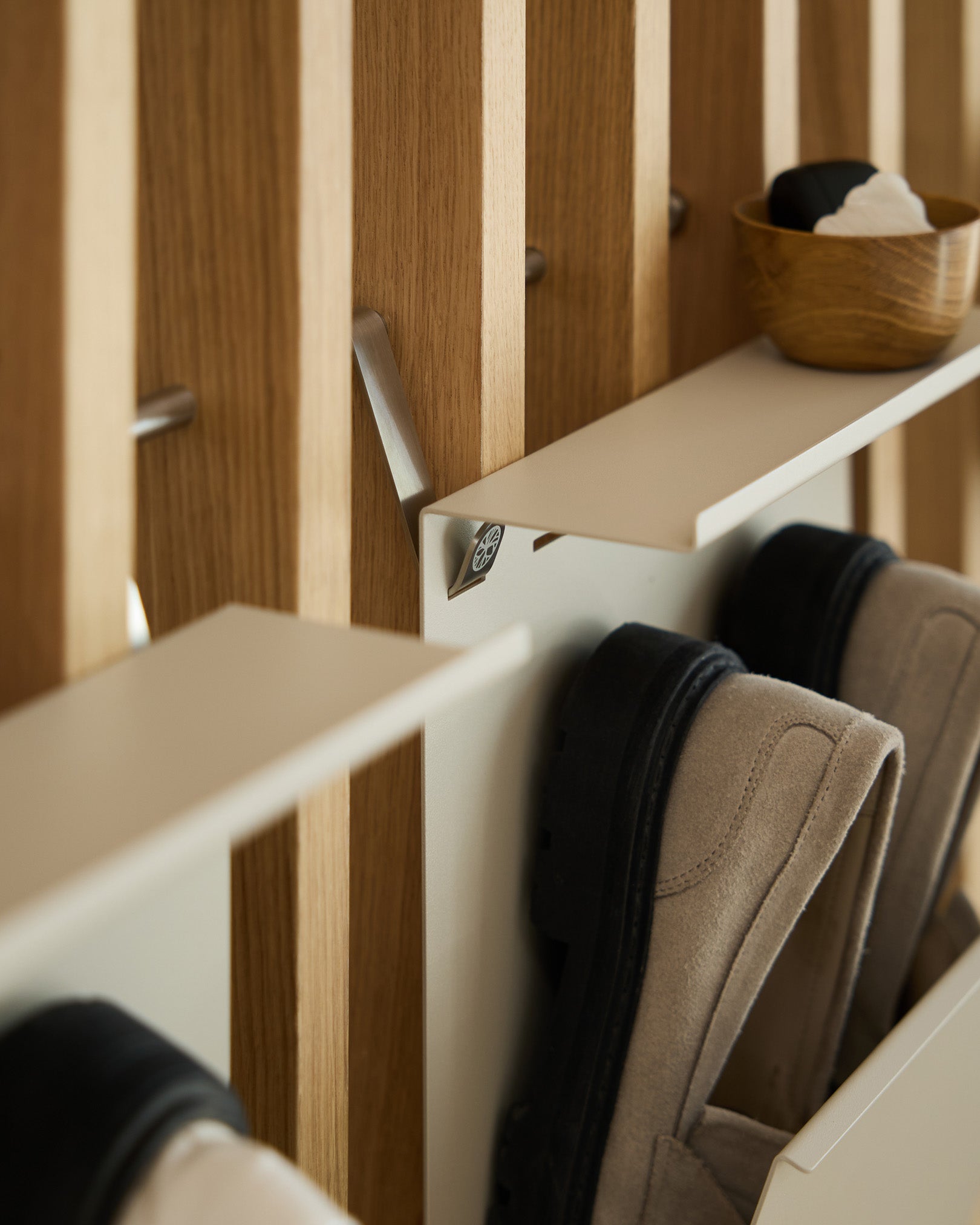 Minimalistisch beige gepoedercoat steel schoenenrek van WoodUpp, gemonteerd op een Nordisch lattenpaneel Akoestisch paneel, met daarboven een small kom voor sleutels.