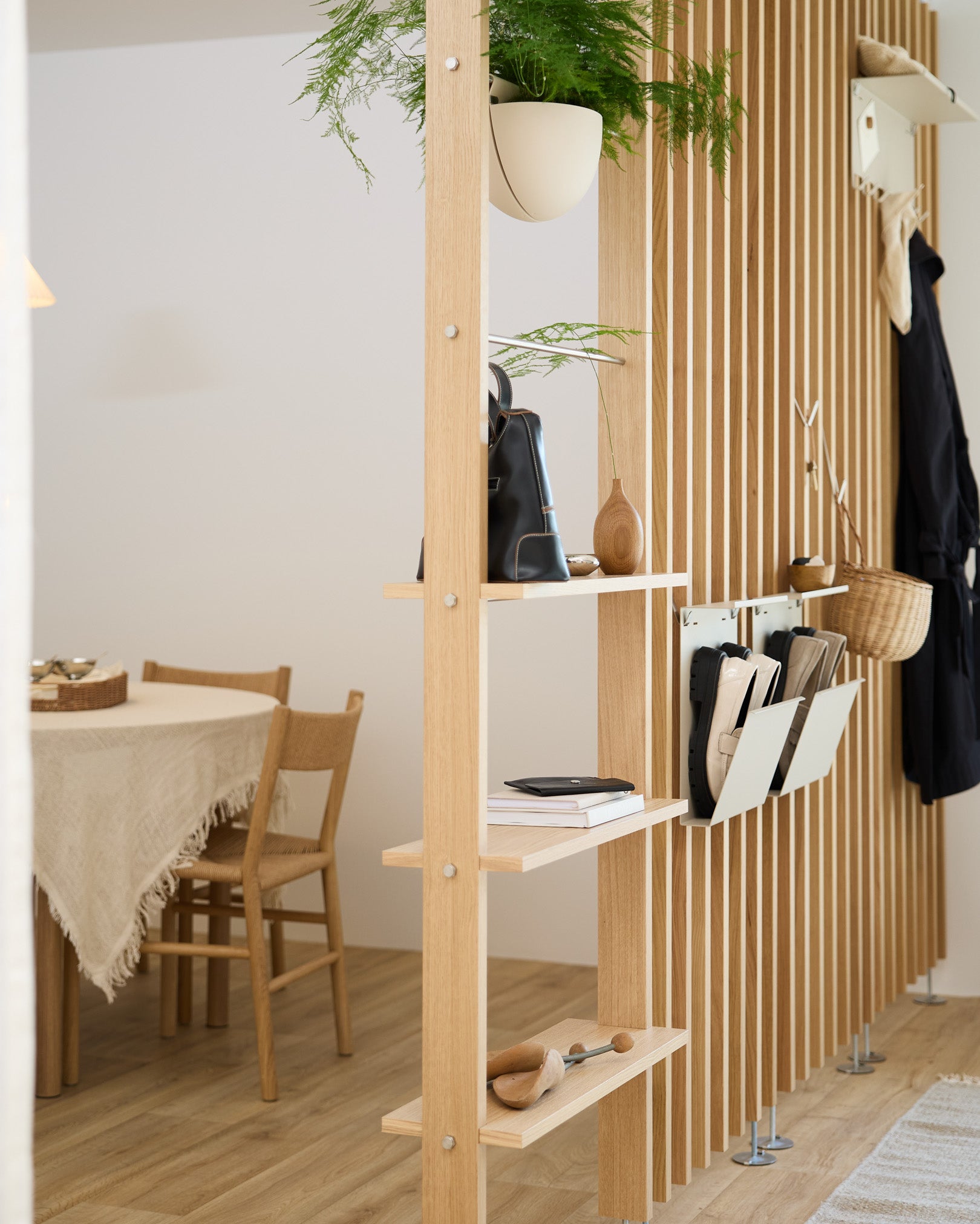 Open houten planken verdelen de eetruimte, met Nell Schoenenopberger in beige van WoodUpp voor een geordende schoenenplek in een modern Scandinavisch huis.