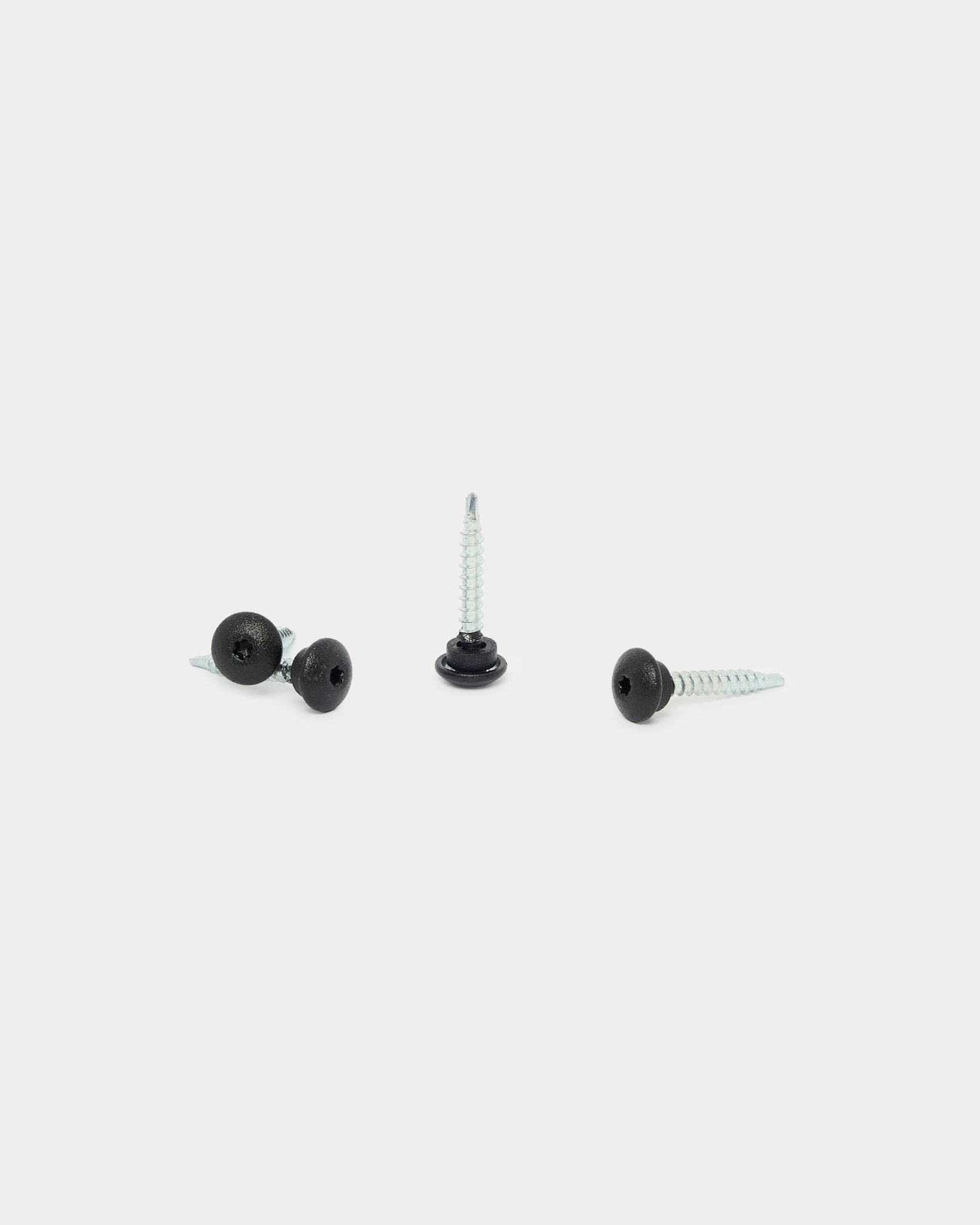 Drie black WoodUpp 4.8x35-schroeven met Ø9.5-ringen op een witte achtergrond, ontworpen als bevestigingsmateriaal voor Aluwood-gevelpanelen voor buiten.