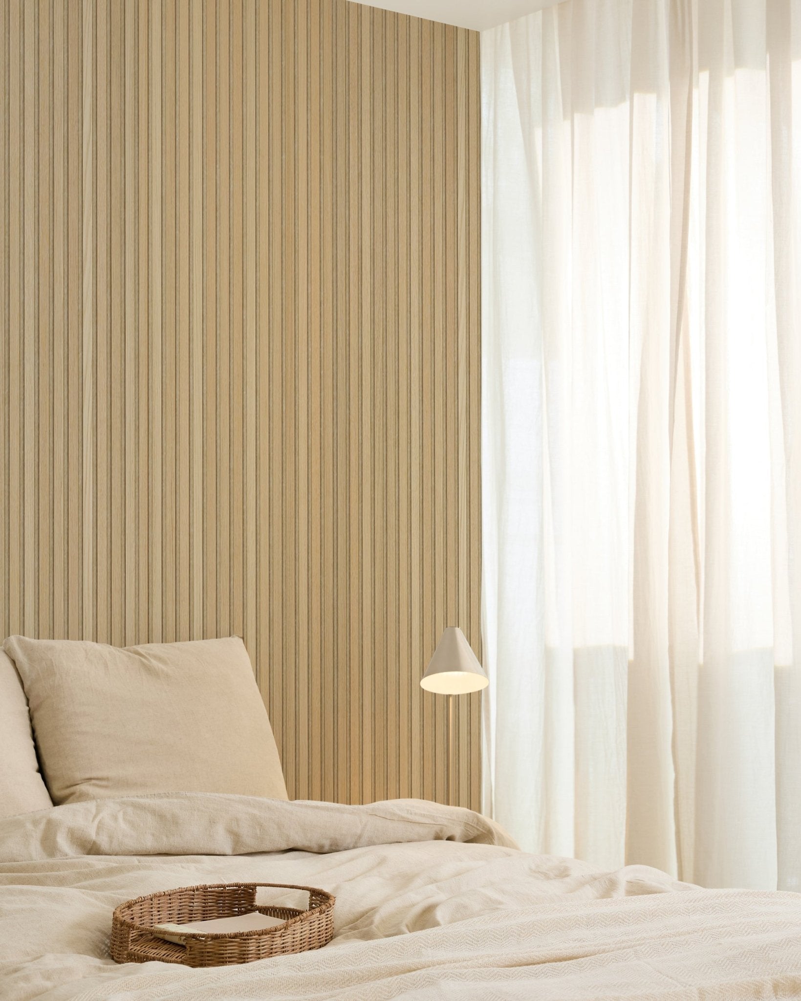 Minimalistische slaapkamer met beige beddengoed, een rieten dienblad, een moderne wandlamp, een Akupanel accentwand van akoestische houten panelen en transparante gordijnen die zacht natuurlijk licht filteren.