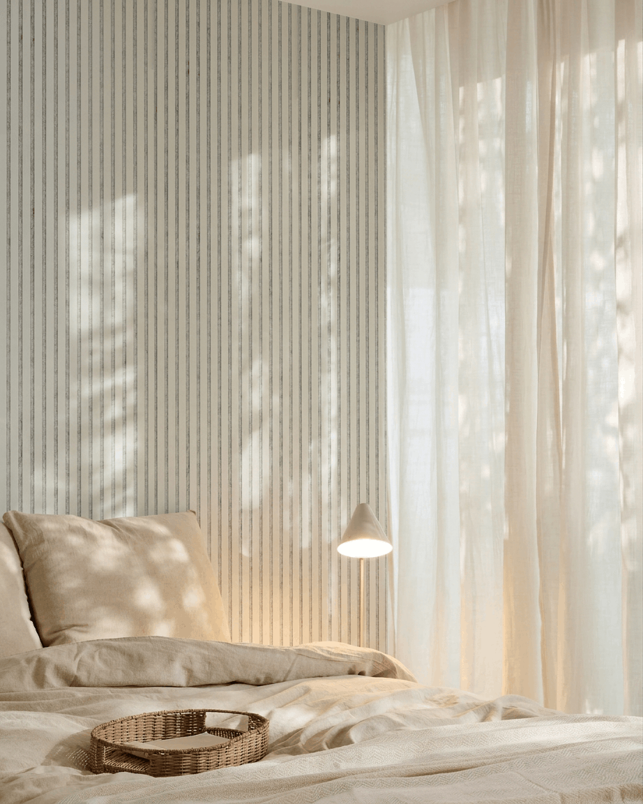 Minimalistische slaapkamer met beige beddengoed, een rieten dienblad, gestreept behang en een WoodUpp Akupanel akoestisch houten paneel in Snow Grey Felt voor geluidsabsorptie.