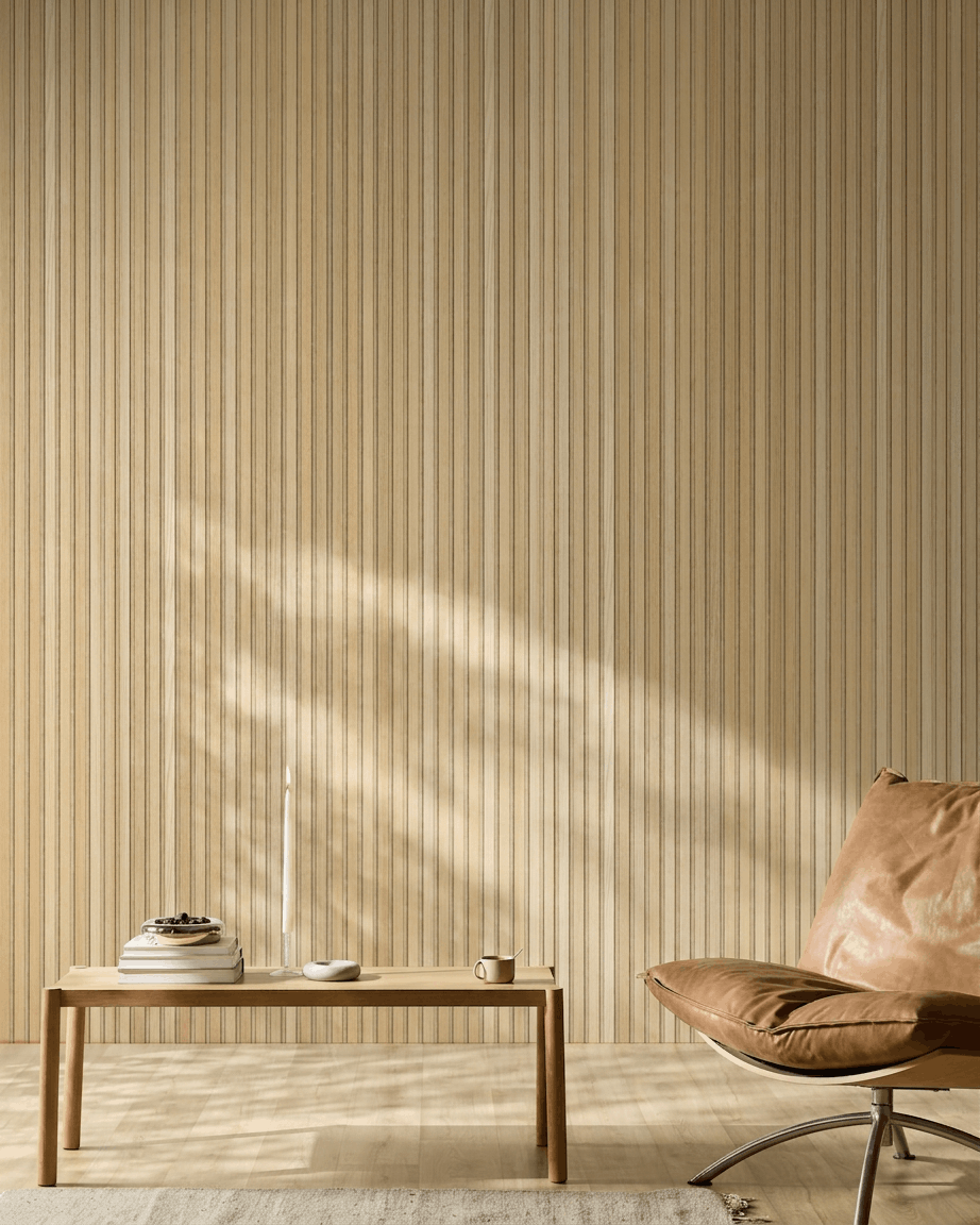 Minimalistische Scandinavische ruimte met een WoodUpp Akupanel akoestisch houten paneel in Natural Wood Classic Oak, een lichtbruine leren stoel en een eenvoudige houten tafel met sfeervolle accenten.