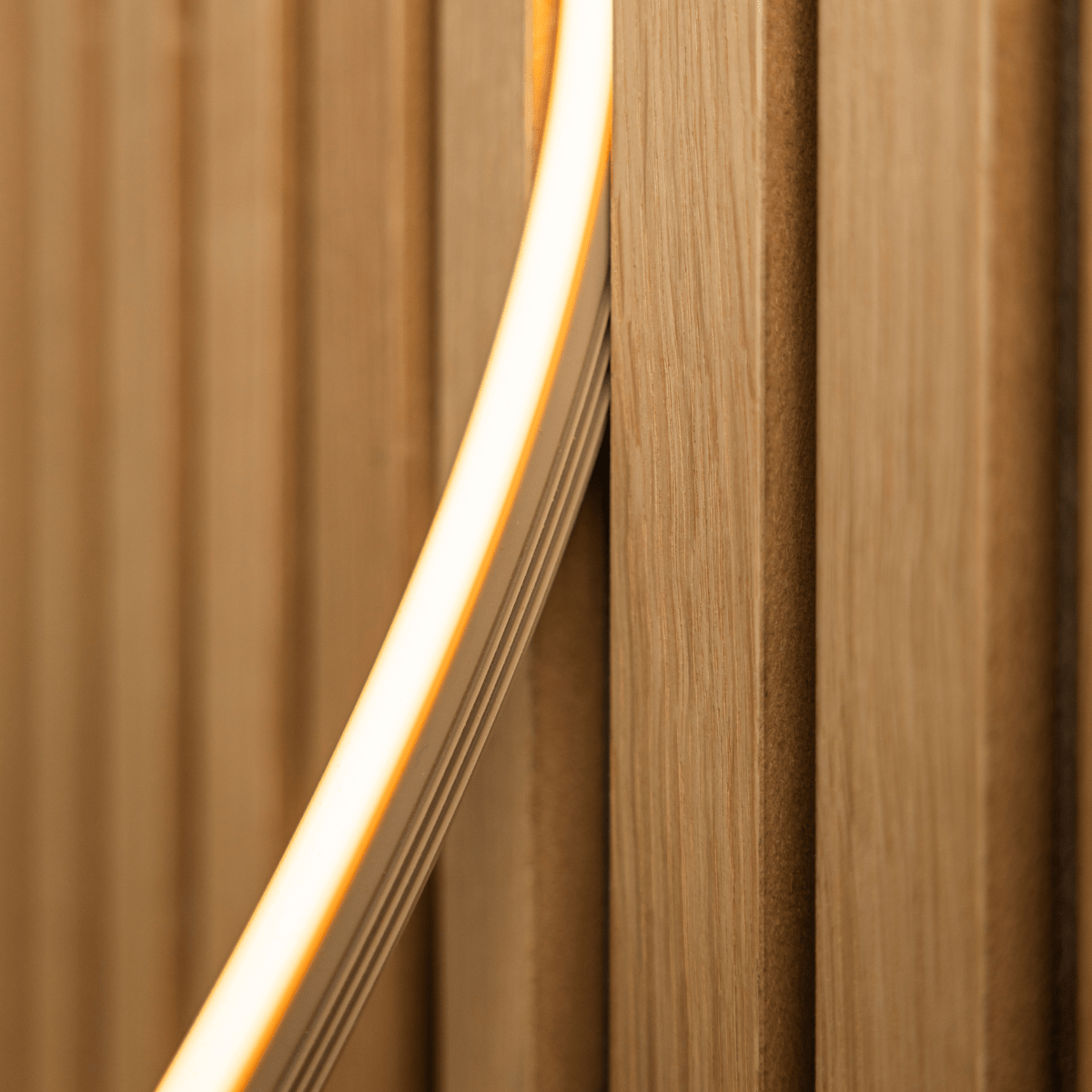 Close-up van WoodUpp Lumi ledstrip in beige (240 cm) die warmgeel licht uitstraalt op Akupanel vertical akoestische houten latten; compatibel met Philips Hue.