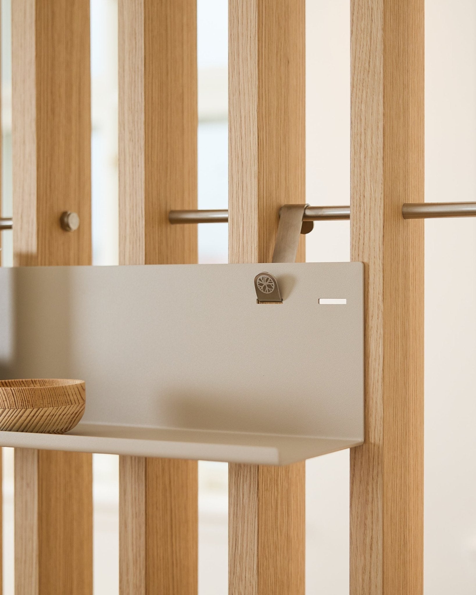 Beige WoodUpp BM1 metalen plank (63 x 13,4 cm), gemonteerd op een vertical akoestisch lattenwandpaneel, met aan de linkerkant van de plank een houten kom.