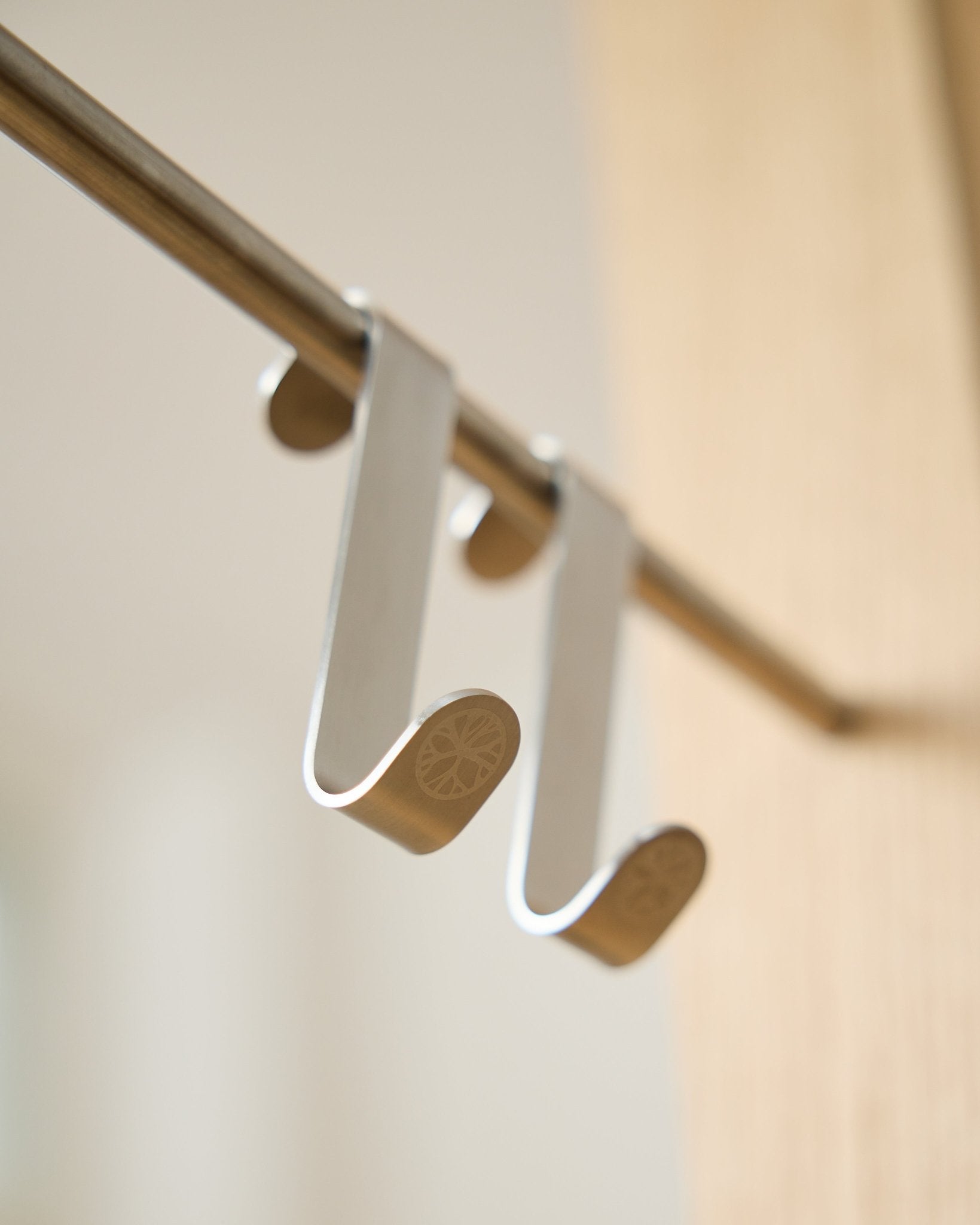 Alva S-Hook BM1  BM2 van WoodUpp, twee roestvrijstalen steel haken met gegraveerde platte uiteinden, ontworpen om accessoires op Akupanel horizontal stangen te hangen.